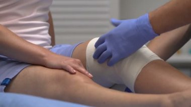 Hasta dizine elastik sargı takan doktor, eklem travması, sağlık hizmetleri
