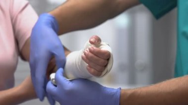 Doktor kadın hasta koluna elastik bandaj takıyor, eklem çıkığı var.