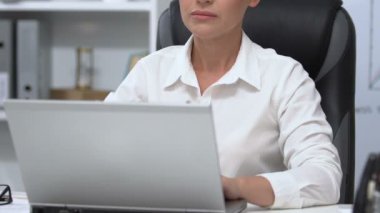 Ofiste dizüstü bilgisayarda çalışan ciddi bir iş kadını, önemli bir proje, yakın plan.