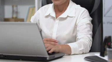 Dizüstü bilgisayarda çalışan kadın karnına dokunuyor, mide iltihabı, düzensiz beslenme...