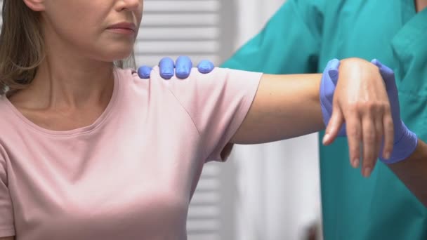 Реабилитатолог перемещает женскую руку, лечение после травмы или операции — стоковое видео