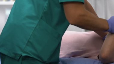 Spor doktoru kadın hasta kolunu hareket ettiriyor, travma rehabilitasyonu, tedavi