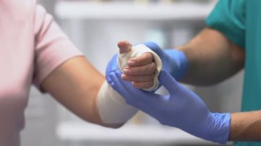 Doktor kadın hasta kolunu elastik bandajla muayene ediyor, eklem yaralanması, travma.