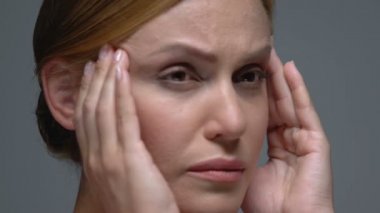 Mutsuz bir kadın, acı veren tapınaklara masaj yapıyor, baş ağrısı çekiyor, migren sorunu yaşıyor.