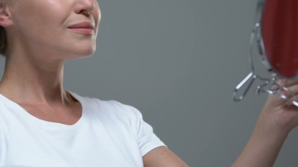 Mujer mirando en el espejo, disfrutando de la belleza, resultado del procedimiento cosmetológico — Vídeos de Stock