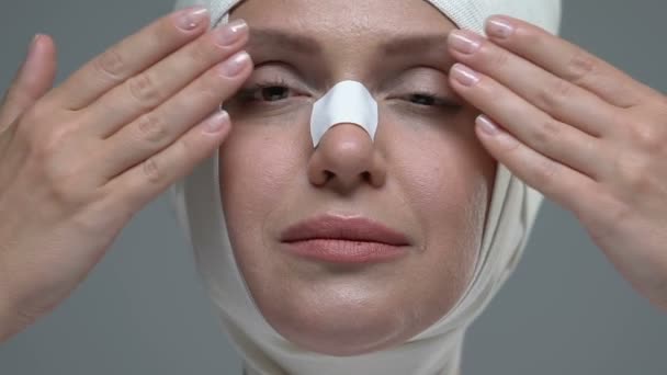 Woman in elastic bandage on face opening eyes, enjoying plastic surgery result — Stock Video