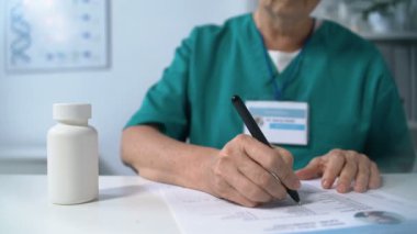 Hasta ilaç formunu dolduran, gözlük takan, ilaç kullanan kadın doktor.