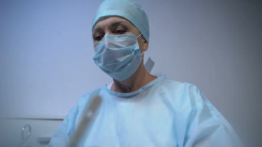 Olgun doktor, sorumluluk gerektiren ameliyatlar yapıyor. Alnındaki teri siliyor.