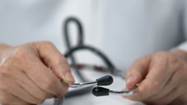 Doktor steteskop takıyor ve kameraya gösteriyor, düzenli sağlık kontrolü.