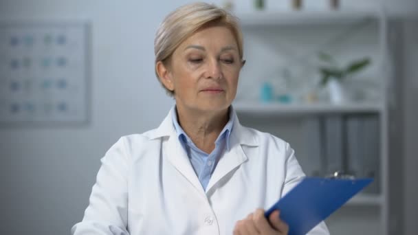 Doutor em seus 50 anos propondo assinar seguro médico na câmera, cuidados de saúde — Vídeo de Stock