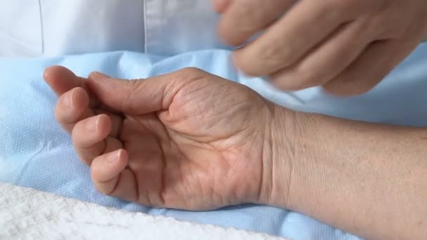 Médico tocando la mano inconsciente del paciente después de la cirugía, comprobando el pulso, ayuda — Vídeo de stock