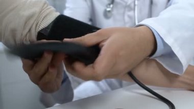 Atardamar gerilimini ölçen erkek doktor, düzenli sağlık kontrolü.