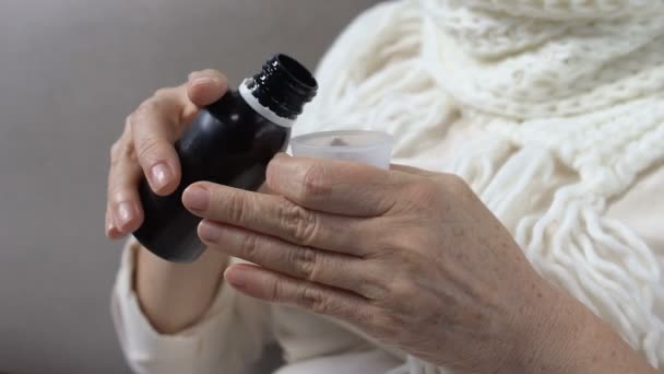 Зрелая женщина в шарфе принимает отвратительный сироп от кашля, лекарство от гриппа — стоковое видео