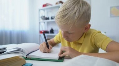 Akıllı erkek çocuk ödev yapıyor, deftere, eğitime ve bilgiye yazıyor.