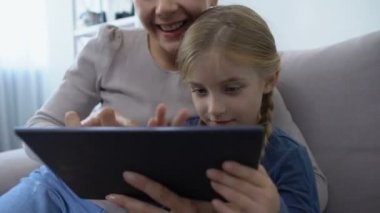 Anne ve kızının mutlu bir ailesi var. Tablette oyun oynuyorlar, eğleniyorlar.