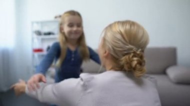 Sevimli küçük bir kız koşuyor ve annesine sarılıyor, çocuklar seviyor ve anne babasıyla ilgileniyor.