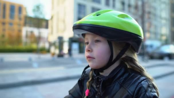 Uppmärksam liten flicka i sporthjälm sitter på cykel, redo att rida utomhus — Stockvideo