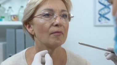 Otolaryngologist yaşlı kadın boğazını, anjin belirtilerini ve tedaviyi kontrol ediyor.