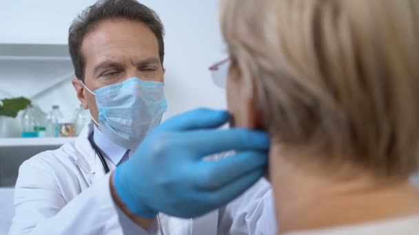 男治疗师戴面具检查女病人淋巴腺、心绞痛症状 — 图库视频影像