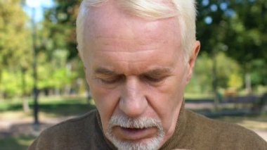 Kafkasyalı gri sakallı adam dışarıda gözyaşlarını siliyor, bunalımda, anıları var.