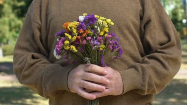 Yaşlı erkeklerin ellerinde renkli bahar çiçekleri, randevu için romantik bir hediye, şefkat