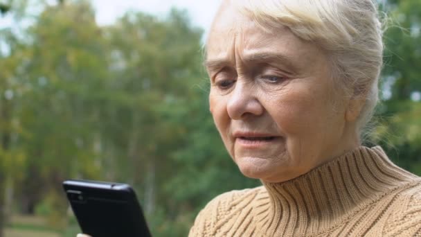 Mujer mayor concentrada escribiendo mensaje de teléfono inteligente al aire libre, conexión en línea — Vídeo de stock