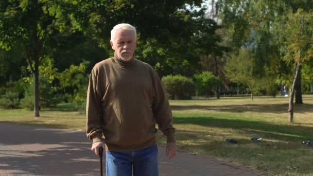 У віці чоловік пенсіонер ходить палицею на відкритому повітрі, старі труднощі у віці, відпочинок — стокове відео