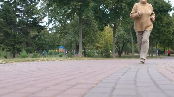 Parkta koşan mutlu yaşlı kadın, dışarıda sağlıklı bir aktivite, yaşlılık refahı. — Stok video