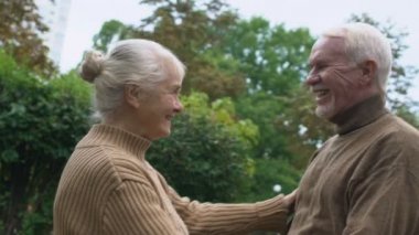 Neşeli romantik bir çift emeklinin açık hava buluşmasında kucaklaşması, şefkatli ilişkiler