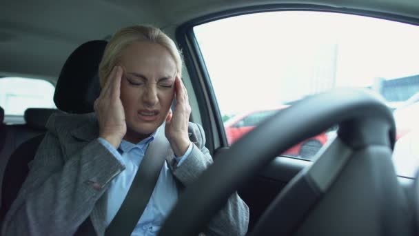 Gammal kvinnlig förare massera tempel, lider fruktansvärd huvudvärk i bilen, smärta — Stockvideo