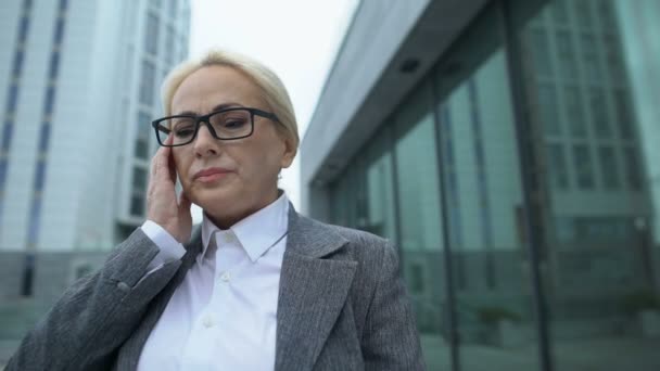 Verouderde zakenvrouw in bril aanraken tempel gevoel sterke hoofdpijn buiten — Stockvideo