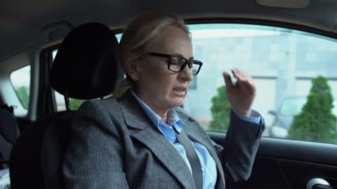 Kadın baş ağrısı çekiyor ve arabada oturup ağrı kesici alıyor.