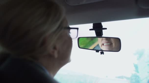 Женщина, смотрящая на свой зуб в зеркало заднего вида автомобиля, жвачки и чувствительности зубов — стоковое видео