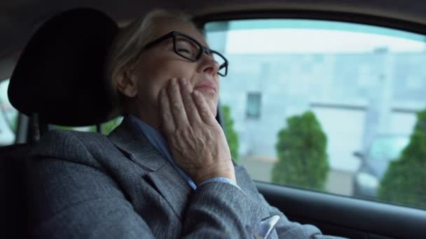 Mujer madura sintiendo dolor de muelas sentado en el coche, caries sensibilidad a las encías prevención — Vídeo de stock