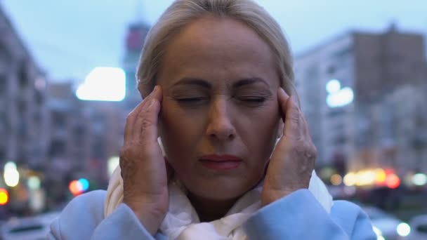 Mujer madura sufriendo dolor de cabeza masaje templos, estrés de la ciudad grande, cansancio — Vídeos de Stock