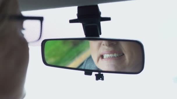 Mujer anciana mirando el diente en el espejo del coche, masajeando la mejilla dolorosa, cuidado dental — Vídeos de Stock