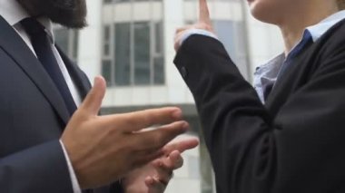 Erkek ve kadın meslektaşlar tartışırken ve el kol hareketi yaparken, çatışma
