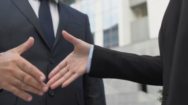 Erkek ve kadın iş ortakları dışarıda el sıkışıyor, başarılı bir anlaşma kapanıyor.