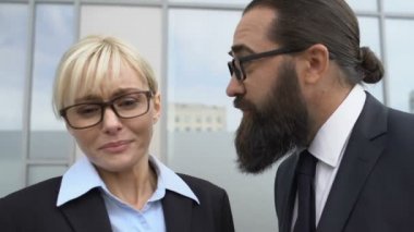 Kızgın erkek patron dışarıda kadın ofis çalışanına bağırıyor, bayan jestleri duruyor.