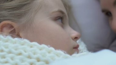 Anne hasta kızın yanında yatıyor ve onu alnından öpüyor.