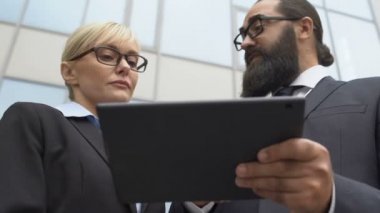 İş ortakları tablet projesini tartışıyor ve gülümsüyor, başarılı işbirliği