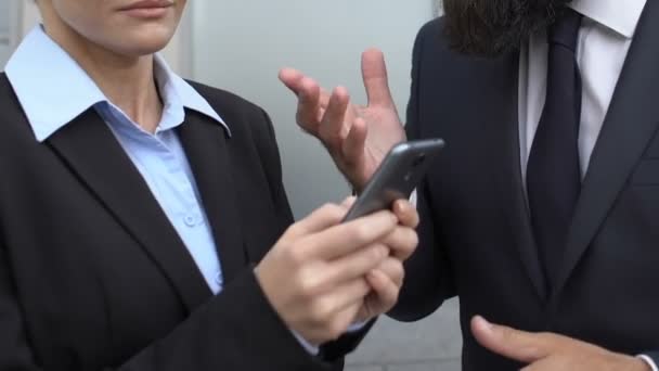 Empresario de traje regañando secretaria femenina desplazándose teléfono al aire libre, plazo — Vídeo de stock