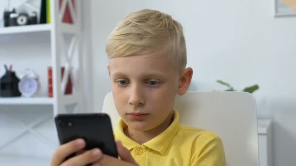 Μικρό αγόρι που χρησιμοποιεί smartphone στο σπίτι, εθισμός σε gadget, επιρροή της τεχνολογίας — Αρχείο Βίντεο