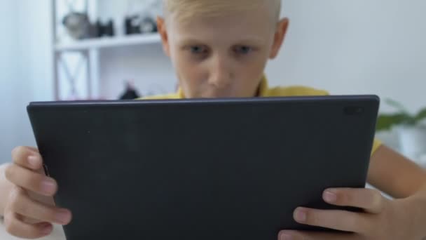 Gadget εθισμένος σχολιαρόπαιδο παίζει video game στο tablet pc, τεχνολογικές επιπτώσεις — Αρχείο Βίντεο