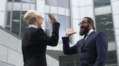 Sakallı iş adamı, kadın meslektaşına beşlik çakıyor, başarıya seviniyor.