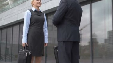 Erkek ofis başkanı yeni işçiyle tokalaşıyor, selamlıyor ya da işbirliği yapıyor.
