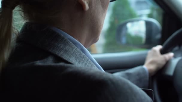 У віці жінка-водій масажує болючу шию в машині, сидячий спосіб життя, здоров'я — стокове відео