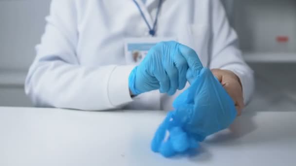 Женщина-терапевт надевает защитные перчатки и готовится проверить пациента, POV — стоковое видео