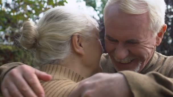 Стареющие муж и жена обнимаются в парке, семейные связи, нежные отношения — стоковое видео