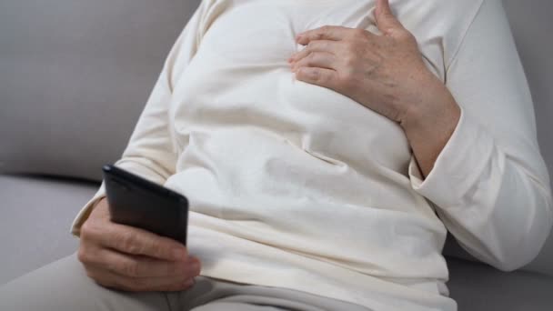 Äldre dam som lider av hjärtvärk, sms 911 nummer på smartphone, hjälp — Stockvideo